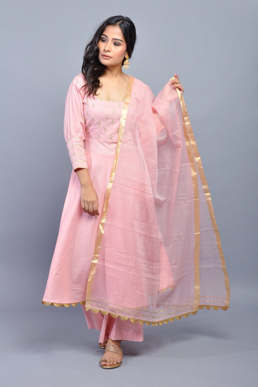 Woman wearing a light pink ethnic kurta set with gold embroidery and organza dupatta