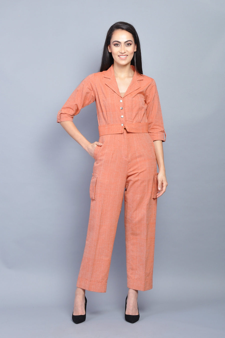 Woman wearing an orange button-down collared jumpsuit with 3/4 sleeves and cargo-style pockets