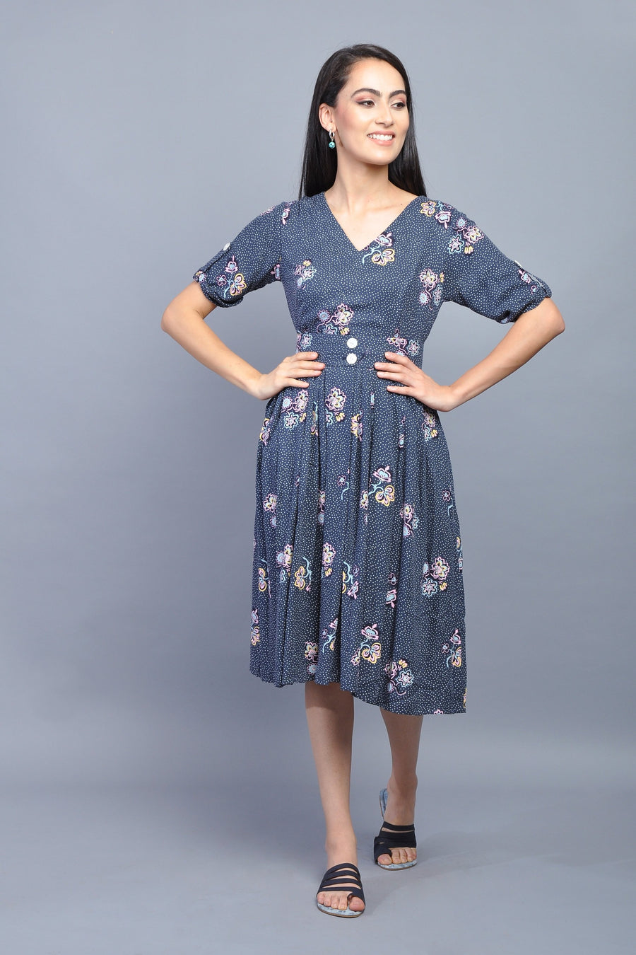 Woman wearing a navy blue floral midi dress with puff sleeves and button detailing.